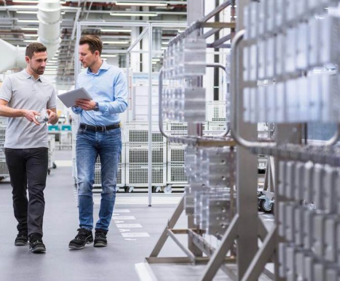 Two man walking in a factory one holding a tablet